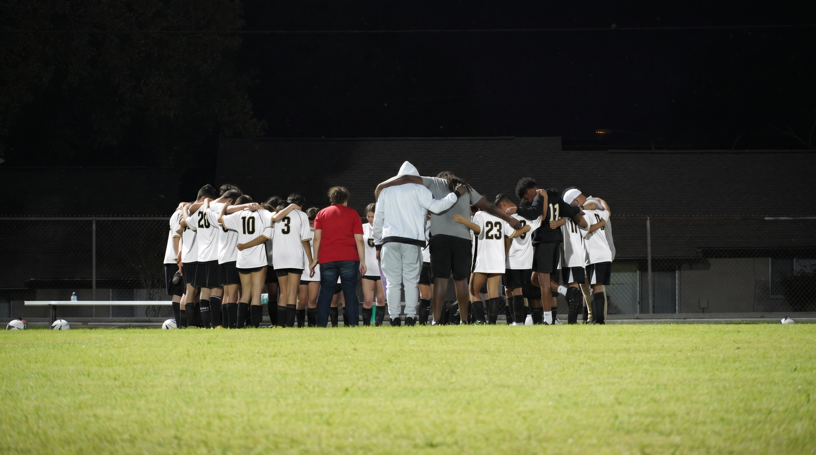 Panthers FC team huddle at night under field lights